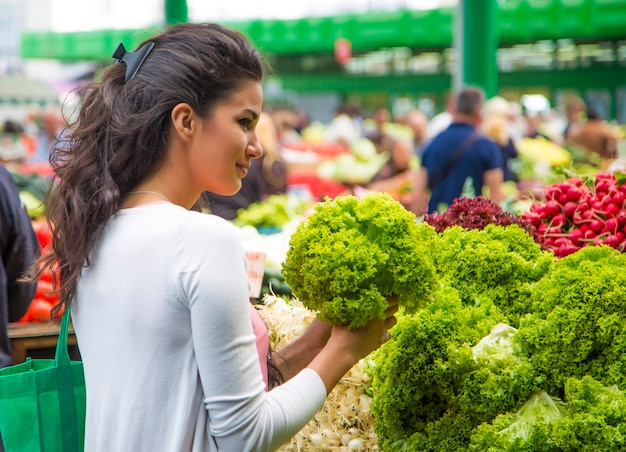 Kaufende Gemüse der recht jungen Frau auf dem Markt