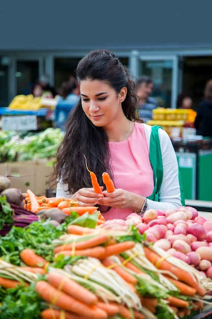 Kaufende Gemüse der recht jungen Frau auf dem Markt