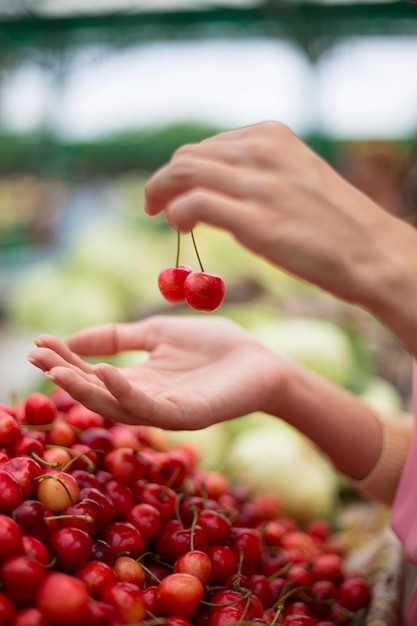 Kaufende Kirschen der jungen Frau am Markt