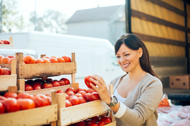 Kaufendes Gemüse der recht jungen Frau auf dem Markt.