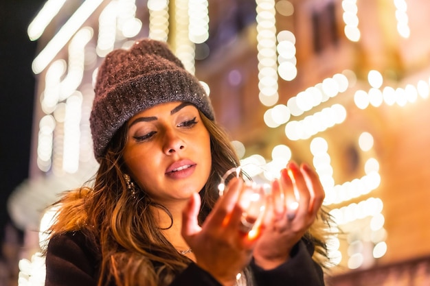 Kaukasier in der Stadt bei Nacht neben Weihnachtslichtern