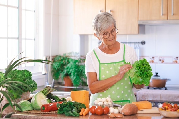 Kaukasische ältere Frau in der Küche zu Hause, während sie Gemüse für eine gesunde Ernährung zubereitet