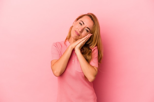 Kaukasische blonde Frau isoliert auf rosafarbenem Hintergrund gähnend und zeigt eine müde Geste, die den Mund mit der Hand bedeckt.