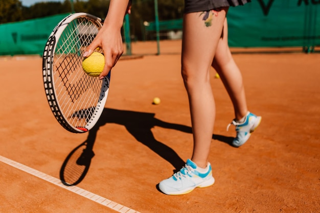 Kaukasische Europäerin hält gelbgrünen Ball beim Tennisspiel auf Sandplatz