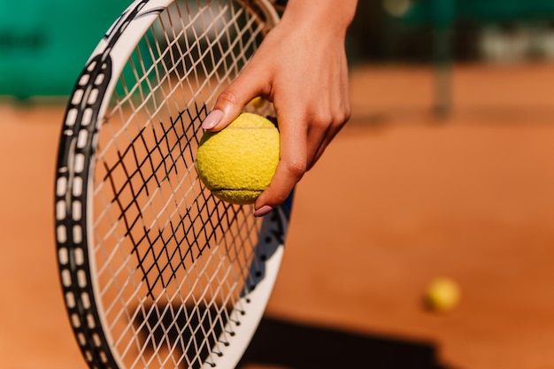 Kaukasische Europäerin hält gelbgrünen Ball beim Tennisspiel auf Sandplatzoberfläche