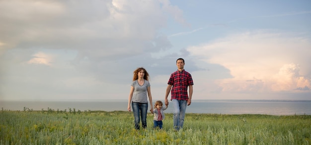 Kaukasische Familie Mama Papa und kleiner Sohn bei Sonnenuntergang Eltern und Kleinkind Junge auf dem Hintergrund des Himmels Freiheit Konzept der glücklichen Familienbeziehungen