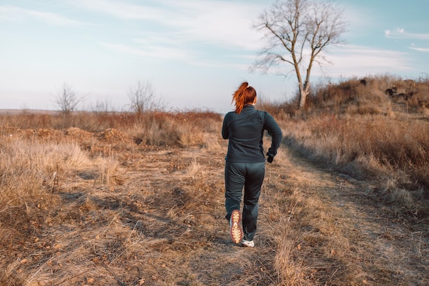 Kaukasische Frau des Läufers, die im Herbstpark gesundes Lebensstilkonzept aktive Sportleute joggt