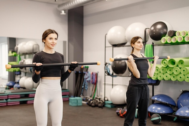 Kaukasische Frau, die Übungen im Fitnessstudio mit persönlicher Trainerin macht