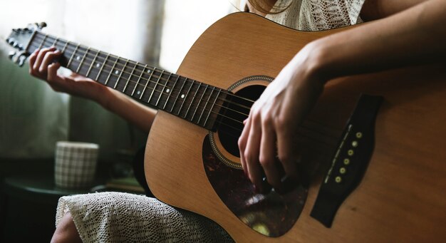 Kaukasische Frau, die Gitarre sich entspannt und spielt