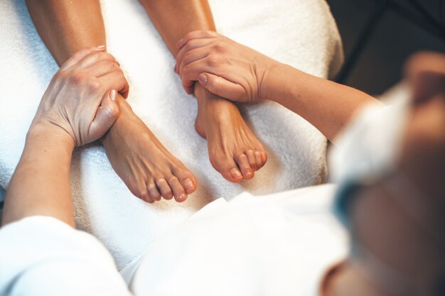 Kaukasische Frau, die in einem Spa-Salon liegt, der eine Fußmassage von einem professionellen Arbeiter hat