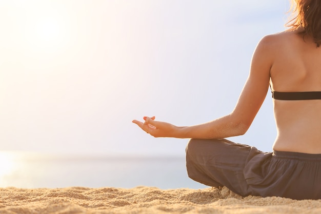 Kaukasische Frau, die Yoga und Übung auf dem tropischen Strand spielt