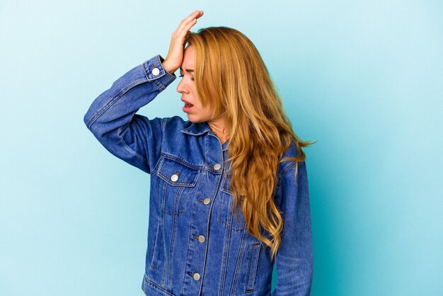 Kaukasische Frau isoliert auf blauem Hintergrund, die etwas vergisst, mit der Hand auf die Stirn schlägt und die Augen schließt.