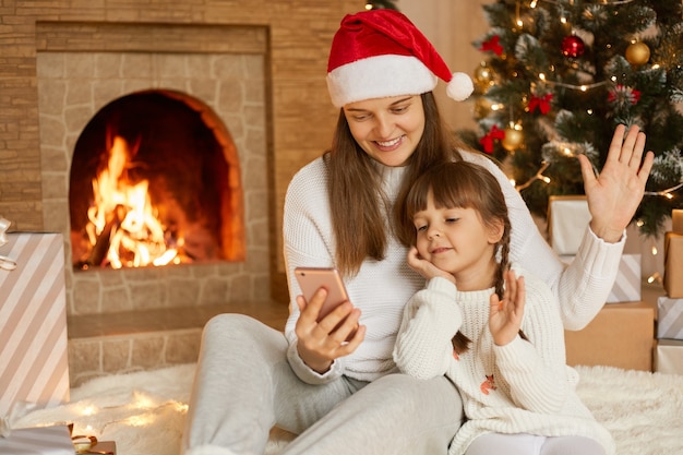 Kaukasische Frau mit ihrer kleinen Tochter an Weihnachten, die Videoanruf hat