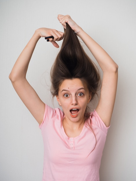 Foto kaukasische frau mit langen haaren, die versucht, selbst einen haarschnitt mit einer schere zu machen, die sich während der pandemie von covid-19 in quarantäne befindet.