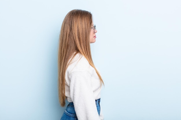 Kaukasische Frau mit roten Haaren in der Profilansicht, die den Raum nach vorne kopiert, denkt, sich vorstellt oder träumt