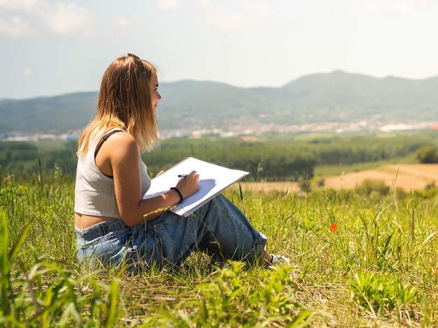 Kaukasische Frau sitzt und zeichnet in der Natur and