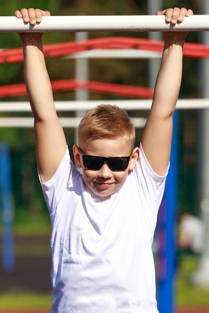 Kaukasische Jugend mit dunkler Brille, die an einer horizontalen Stange hängt