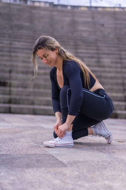 Kaukasische junge Frau, die Fitness in einem Stadtpark macht und ihre Turnschuhe vor dem Training bindet