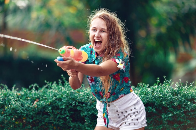 Kaukasische junge Frau kämpft mit Wasserpistole beim Songkran-Festival. Urlaubskonzept/ Thailändisches Neujahr