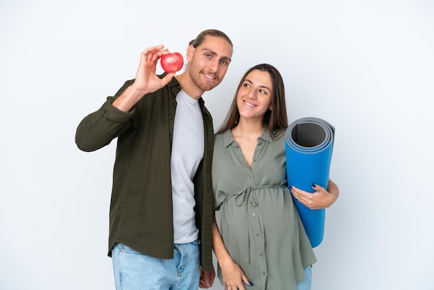 Kaukasische junge Paar isoliert auf weißem Hintergrund schwanger mit einem Apfel und gehen zu Yoga-Kursen