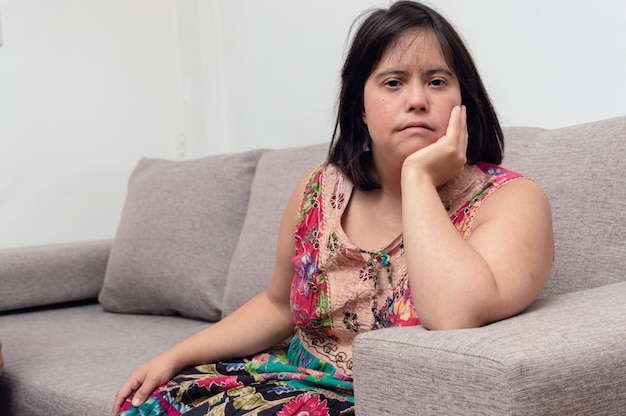 Kaukasische lateinische argentinische erwachsene Frau, die auf dem Sofa sitzt und sich lächelnd auf ihre Hand stützt