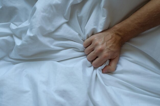 Kaukasische Mannhand, die auf Bett greift
