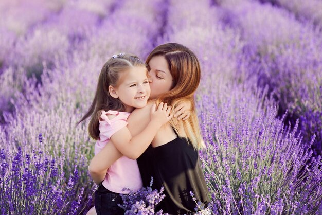 Kaukasische Mutter küsst und kuschelt ihre Tochter im Lavendelfeld. Liebe Friedensfamilie