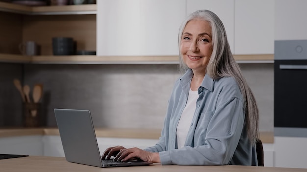 Kaukasische Oberlehrerin ältere Hausfrau Geschäftsfrau Großmutter grauhaarige Dame arbeitet am Laptop