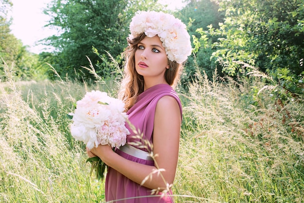 Kaukasische schöne Frau mit einem Kranz aus Pfingstrosen auf dem Kopf Frühlingsblüten-Fee-Konzept