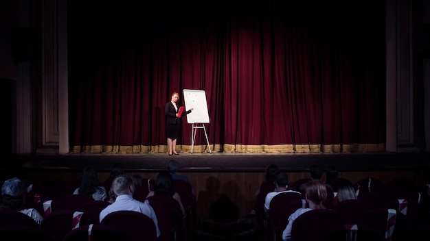 Kaukasische Sprecherin, die eine Präsentation in der Halle einer Universitäts- oder Geschäftszentrumswerkstatt hält