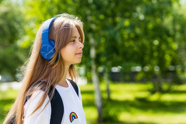 Kaukasische Teenager-Studentin, die im Freien im Stadtpark das Musik-Stereo-Lieblingslied über Kopfhörer hört