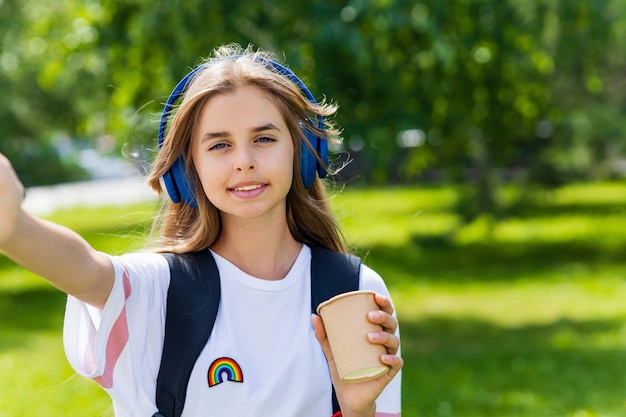 Kaukasische Teenager-Studentin, die im Freien im Stadtpark das Musik-Stereo-Lieblingslied über Kopfhörer hört