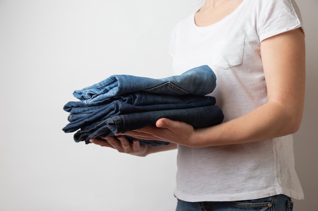 Kaukasische weibliche Hände der Nahaufnahme, die drei Paare blaue Denimjeans halten.