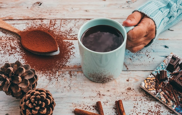 Kaukasische weibliche Hand hält Tasse heiße Schokolade, cremiger und dicker Holztisch