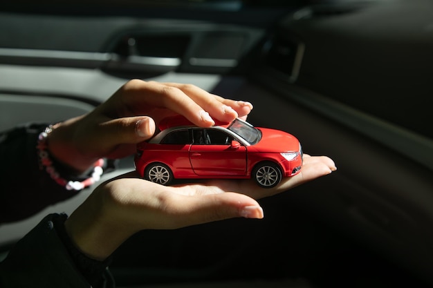 Kaukasische weibliche Hand zeigt ein rotes Spielzeugwagen