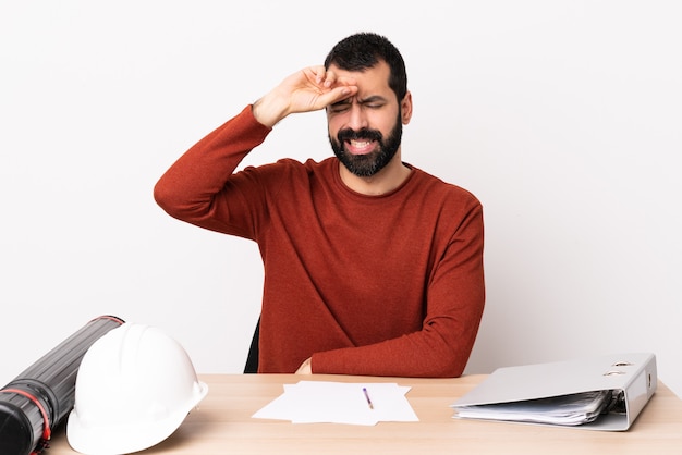 Kaukasischer Architektenmann mit Bart in einem Tisch mit müde und krankem Ausdruck