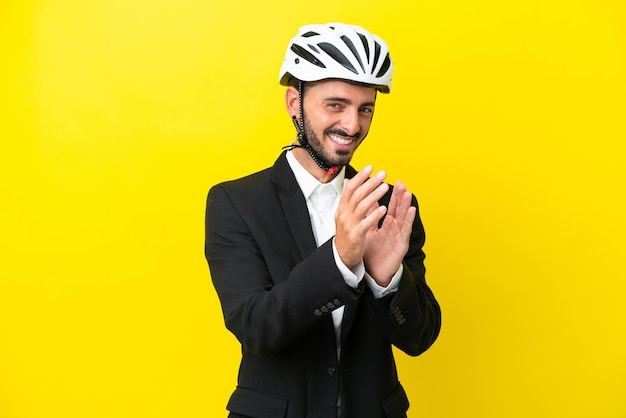 Kaukasischer Geschäftsmann mit Fahrradhelm isoliert auf gelbem Hintergrund applaudiert nach Präsentation auf einer Konferenz