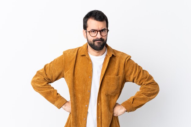 Kaukasischer gutaussehender Mann mit dem Bart, der eine Kordjacke über lokalisierter weißer Wand verärgert trägt