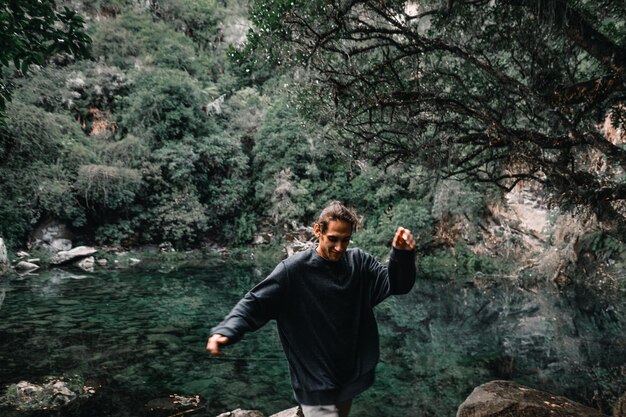 Foto kaukasischer junger mann springt agil und glücklich zwischen den steinen und felsen in der nähe der kleinen transparenten