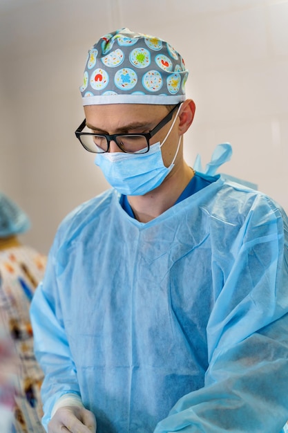 Kaukasischer männlicher Arzt in einem Operationssaal eines Krankenhauses, der eine chirurgische Kappe und eine Maske trägt. Beschäftigte im Gesundheitswesen während des Coronavirus Covid19.