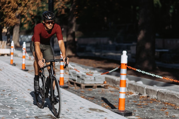 Kaukasischer männlicher Athlet, der Sportkleidung, Helm und Brille trägt und im Radfahren auf den Straßen der Stadt übt. Radprofis trainieren im Sommer regelmäßig an der frischen Luft.