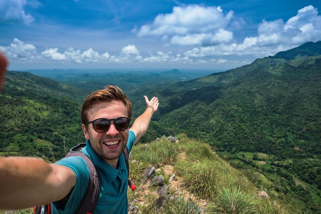 Kaukasischer Mann auf dem Gipfel des Berges, der Selfie vor dem Hintergrund einer hübschen Landschaft macht