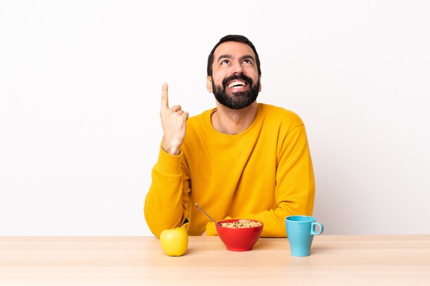 Kaukasischer Mann beim Frühstück in einem Tisch, der nach oben zeigt und überrascht