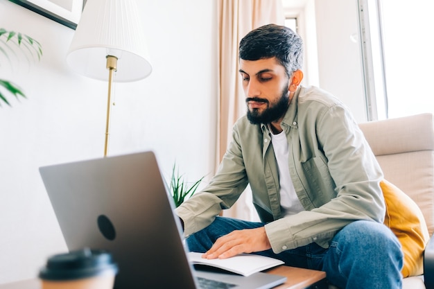 Foto kaukasischer mann college-student, der mit laptop studiert, der sich aus der ferne auf die testprüfung vorbereitet, einen aufsatz zu schreiben, der zu hause hausaufgaben macht, entferntes bildungskonzept.