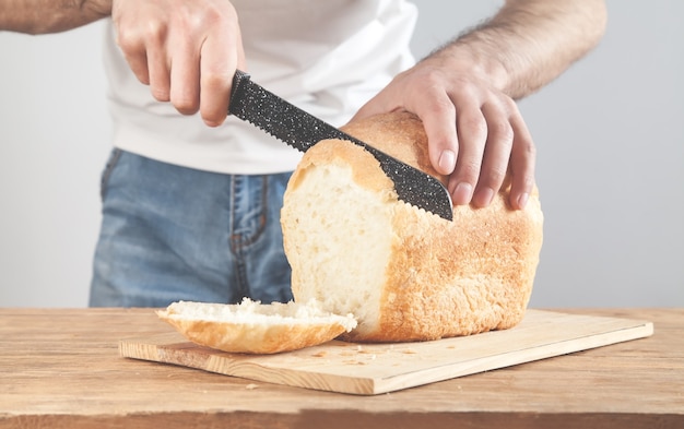 Kaukasischer Mann, der Brot schneidet. Gesundes Lebensmittelkonzept