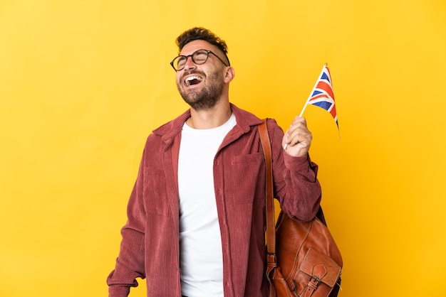 Kaukasischer Mann, der eine britische Flagge hält, die auf gelbem Lachen lokalisiert wird
