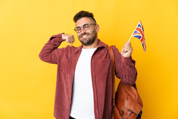 Kaukasischer Mann, der eine Flagge des Vereinigten Königreichs auf gelbem Hintergrund hält und eine starke Geste macht