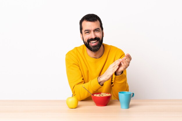 Kaukasischer Mann, der Frühstück in einem applaudierenden Tisch hat