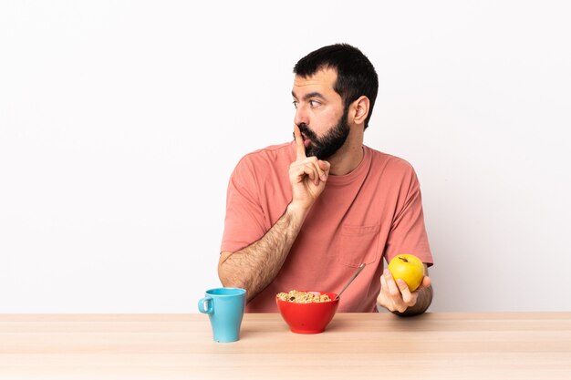 Kaukasischer Mann, der Frühstück in einem Tisch zeigt ein Zeichen der Stille Geste, die Finger in den Mund setzt