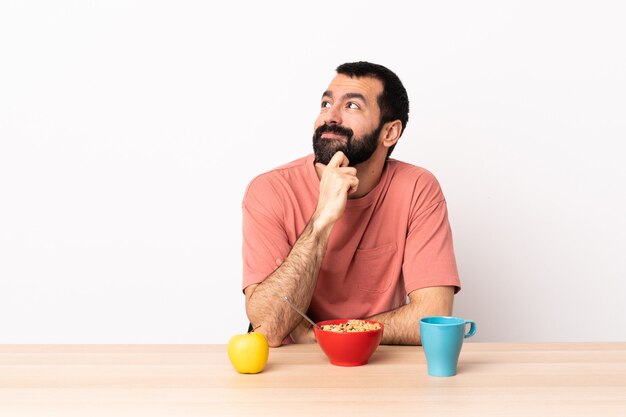 Kaukasischer Mann, der Frühstück in einer Tabelle denkt eine Idee beim Aufschauen
